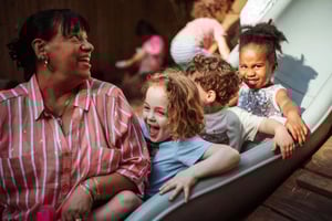 Corlears School teacher Betty having fun on the slide with Early Childhood students